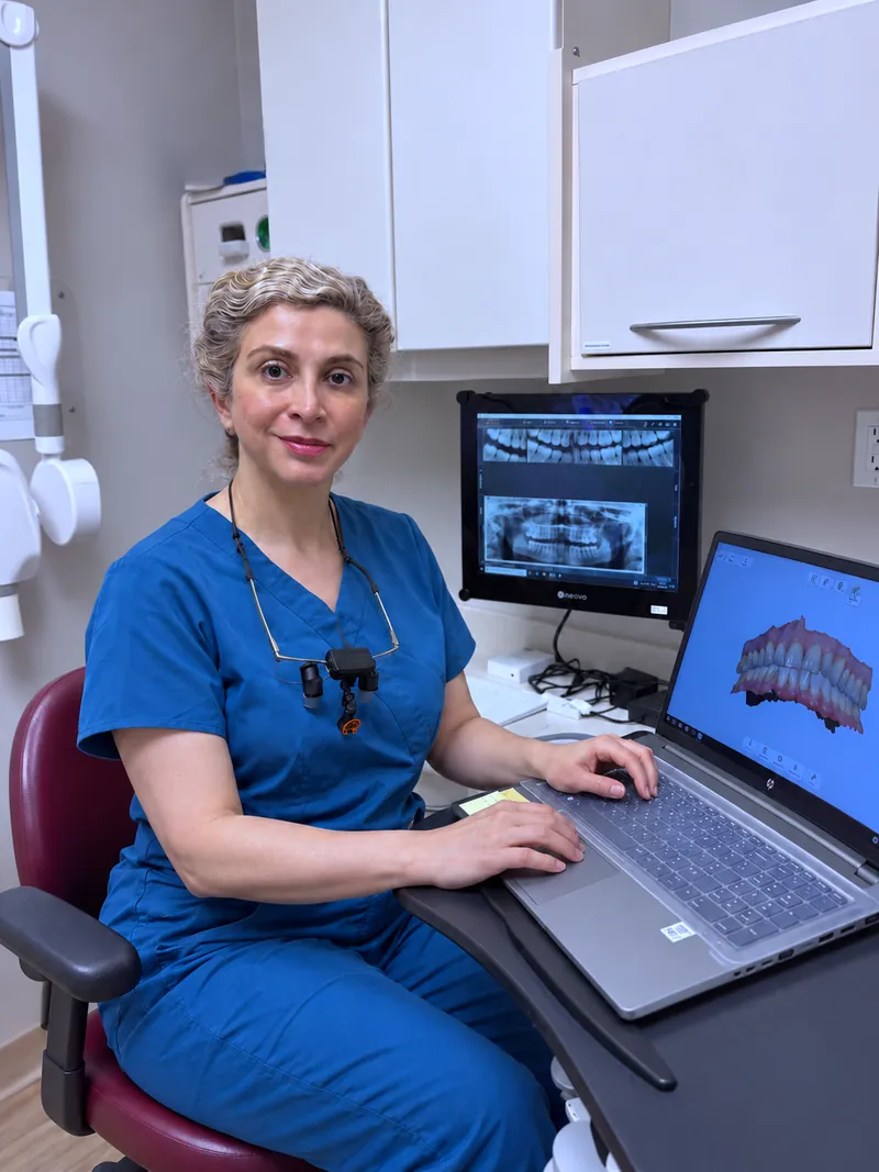 Dentist in blue scrubs reviewing digital dental scans at a clinic